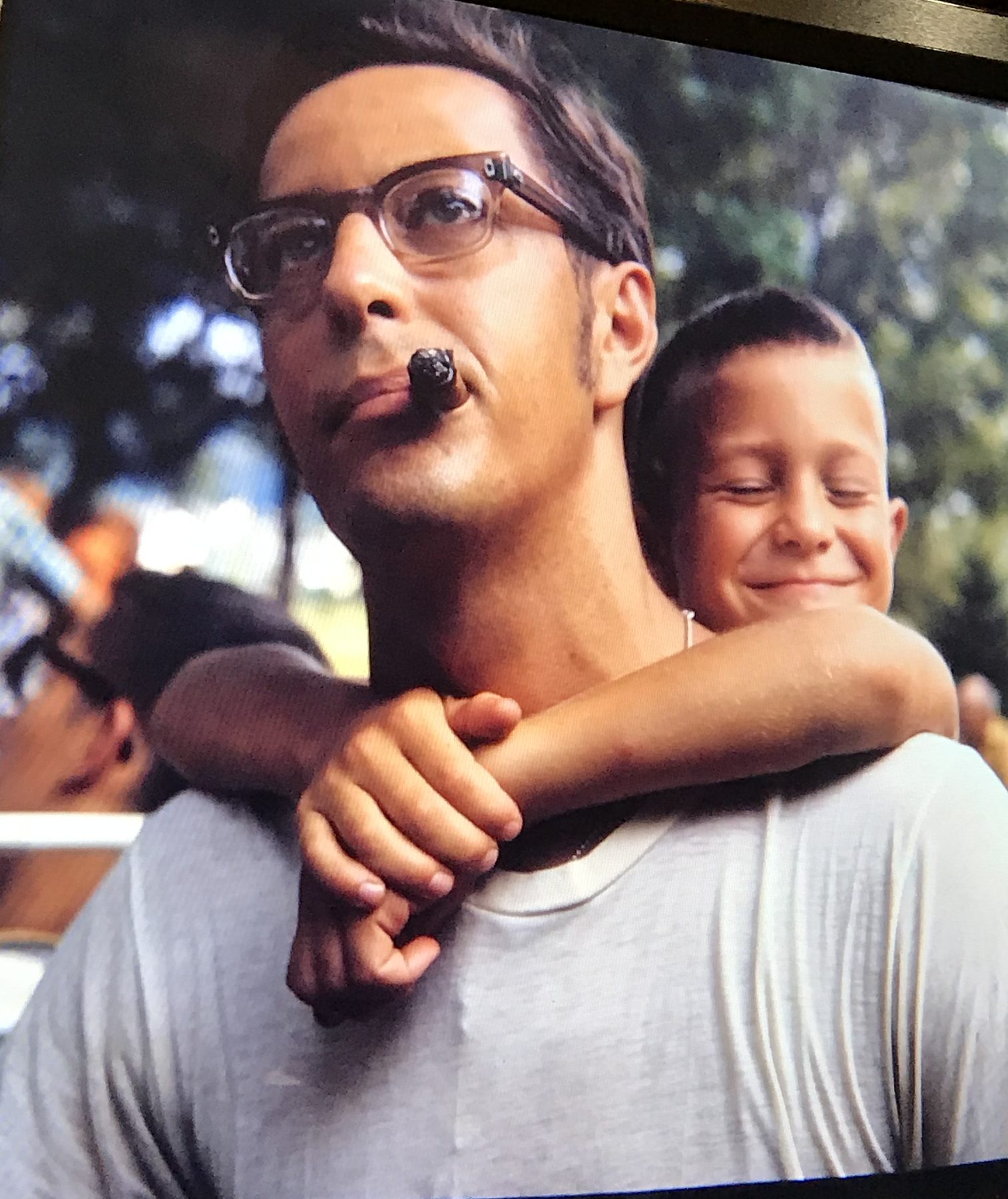 A man with a cigar and a grinning boy on his shoulders